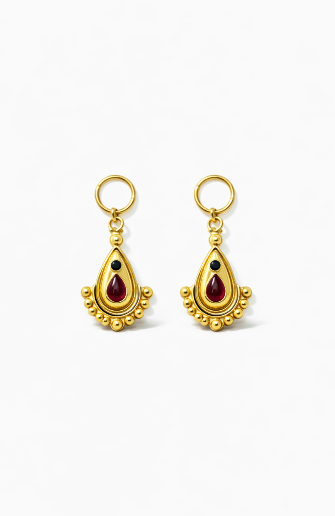 Gold earrings with red gemstones on a white background